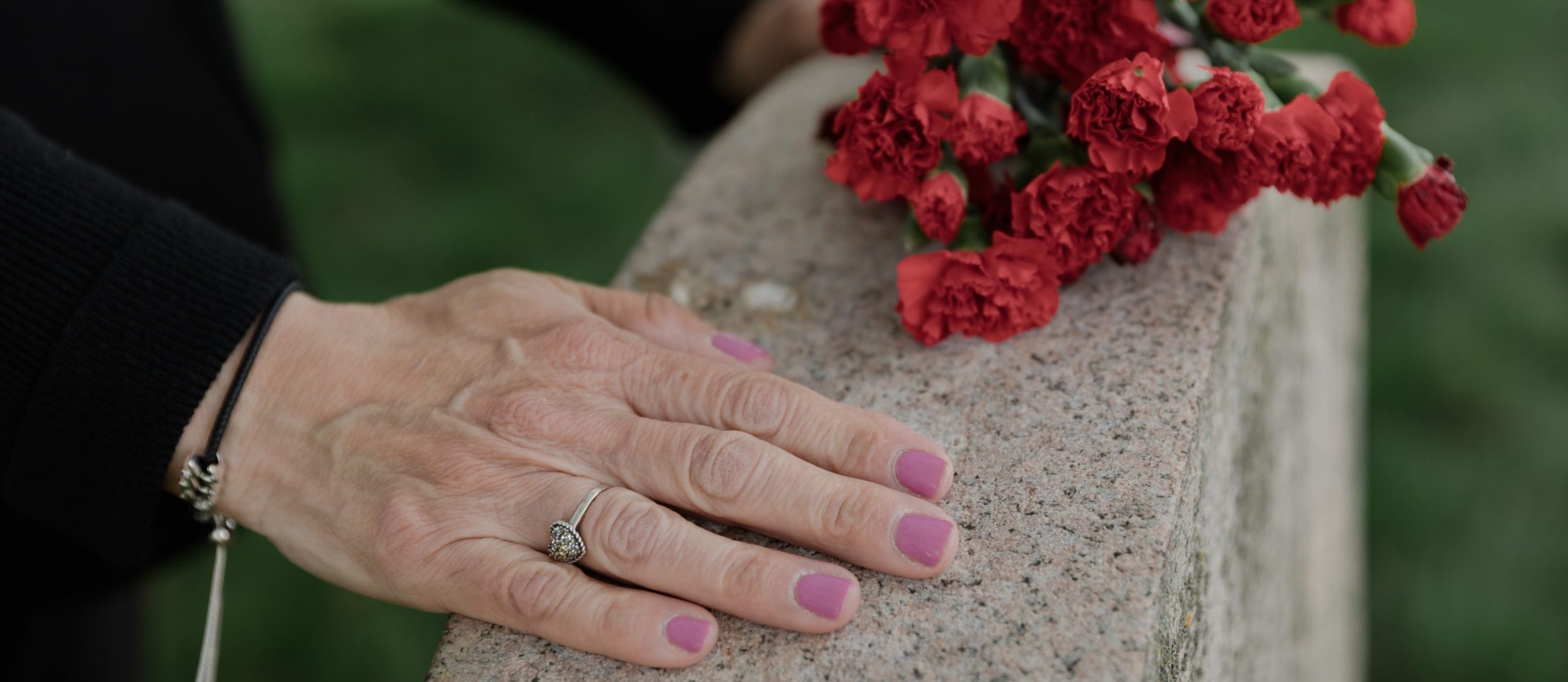 hand and flowers on a gravestone