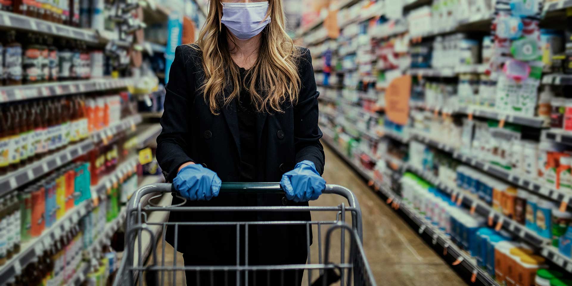 Woman in a face mask wearing latex gloves while shopping in a supermarket during coronavirus