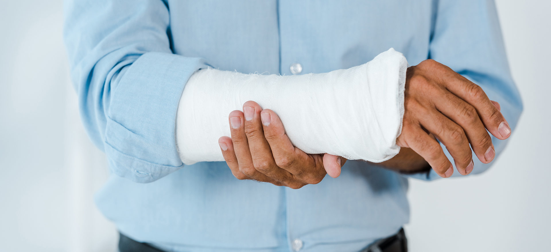 cropped view of injured man touching broken arm wrapped in gypsu